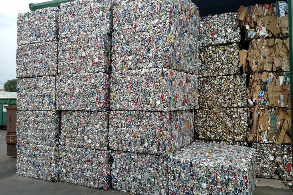 Compacted aluminum cans and cardboard bales stored in a material recovery facility after sorting and baling.